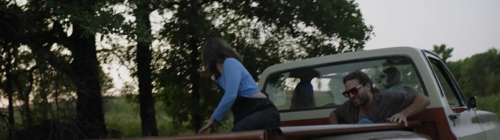 Friends getting out of an old pick truck and running towards a pasture