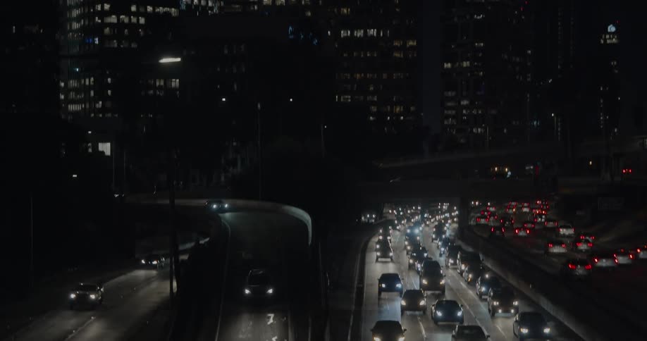 Cars are driving through a downtown city at night