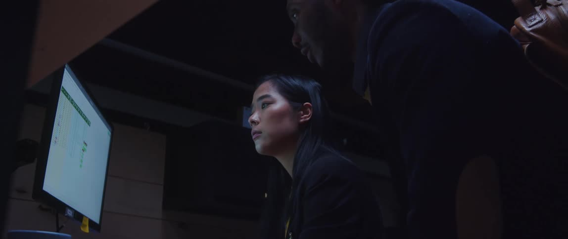 Colleagues discuss a spreadsheet while sitting at a desk in the office