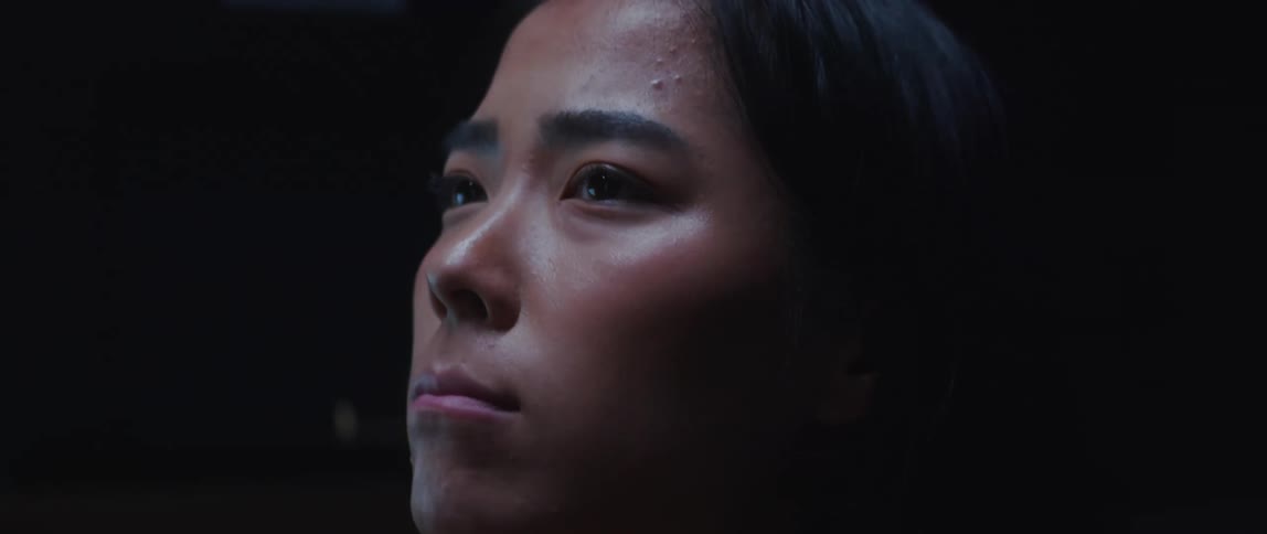 A woman looks around while sitting in a dim room