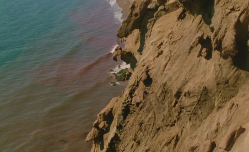 Wavew roll up to base of seaside cliff