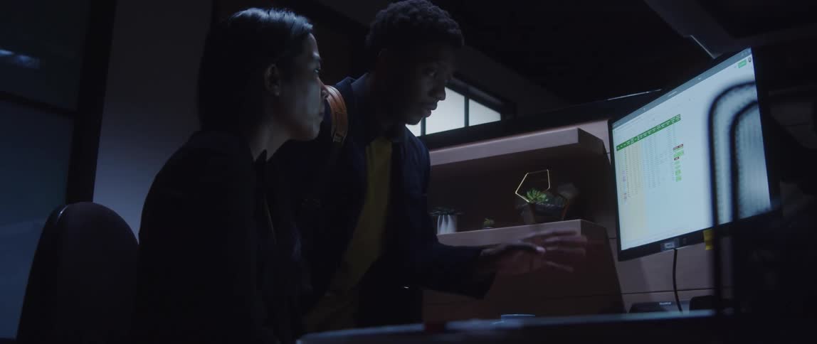 Colleagues discuss a spreadsheet on the computer monitor