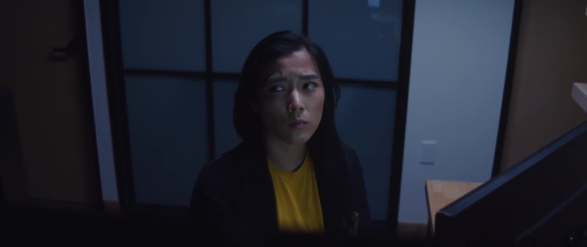 Asian woman looking off contemplatively while working at a computer in an office