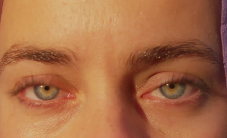 Woman with hazel eyes blinks while wearing a lavender head covering