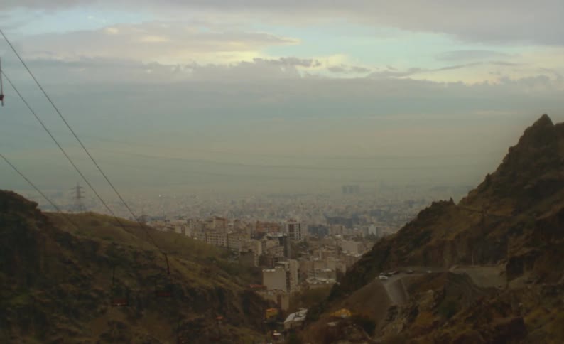 A ski lift descends down over a canyon that overlooks downtown