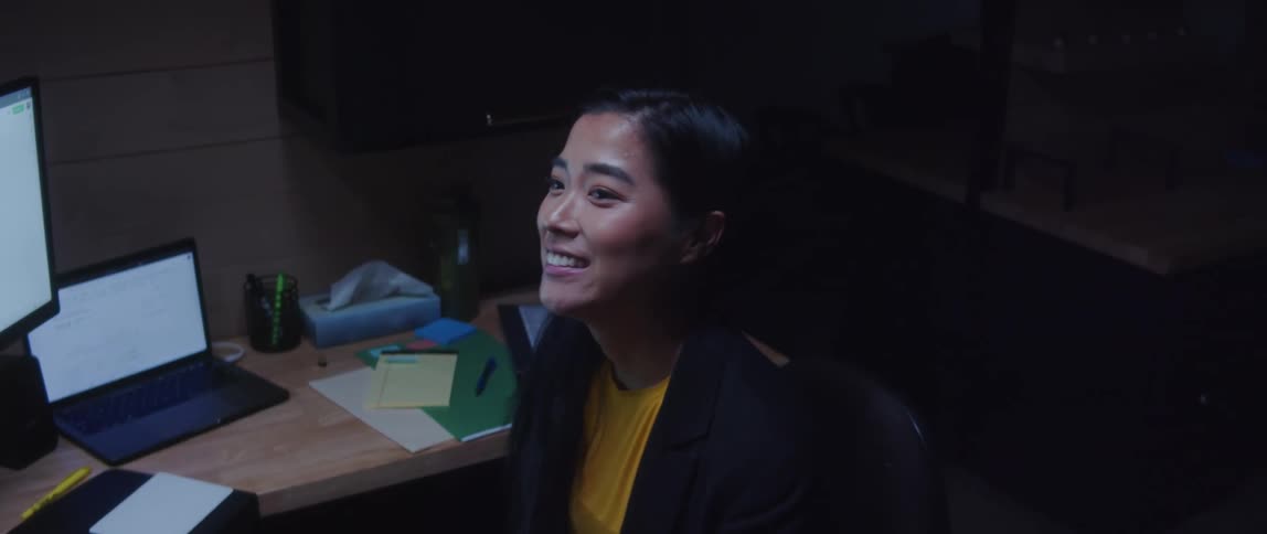 A woman sitting at her office desk says goodbye to a colleague then leans back in her chair