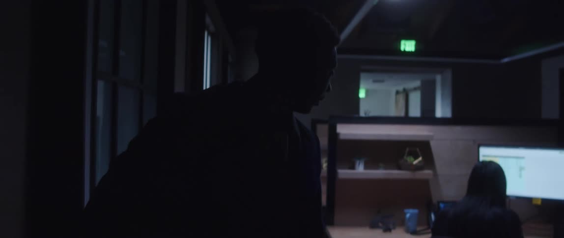 Man in blazer jacket brown sweater and brown backpack switches off lights and leaves the office and says goodbye to a female coworker