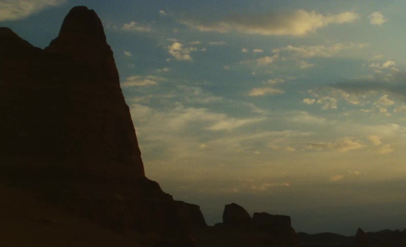 Stone mountain stands partially silhouetted against a cloudy sky