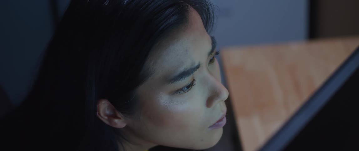 A young woman leans forward to get a closer look at what's on the screen in front of her
