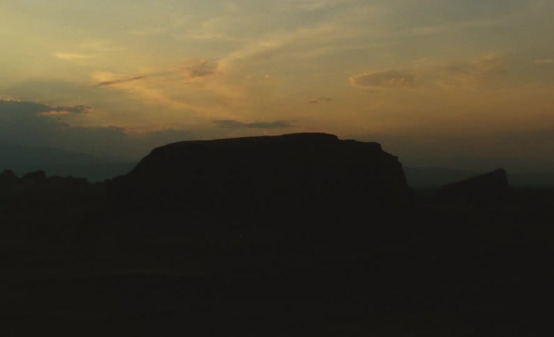 Mounds and hills stand silhouetted against red tinted sky