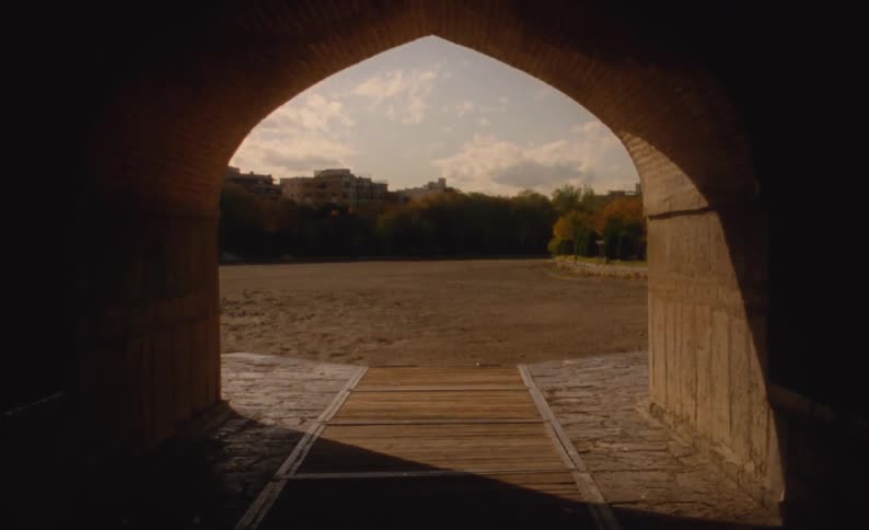 A view of a city and a treeline through the end of a tunnel