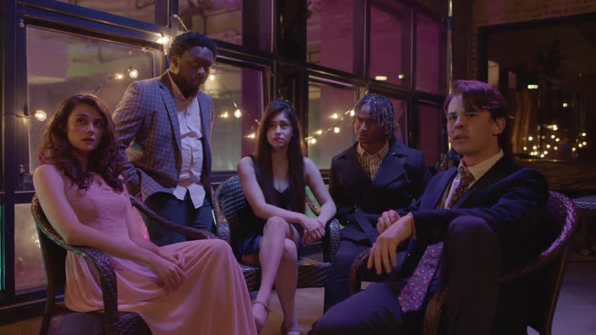 Five friends are hanging out inside and sitting down on a chair