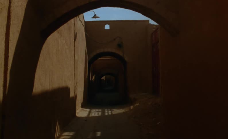 An alley between buildings creating an archway with shadows casting between them