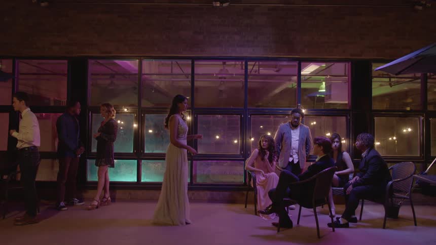 Woman approaches friends sitting together at party and asks if one wants to dance
