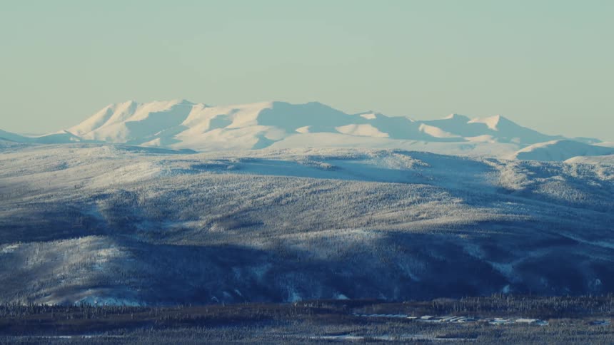 A heavy blanket of snow covers a steep mountain range