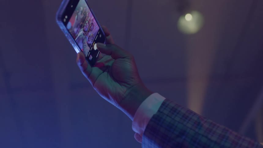 Person wearing shirt and blazer jacket takes selfie with his friends at night club