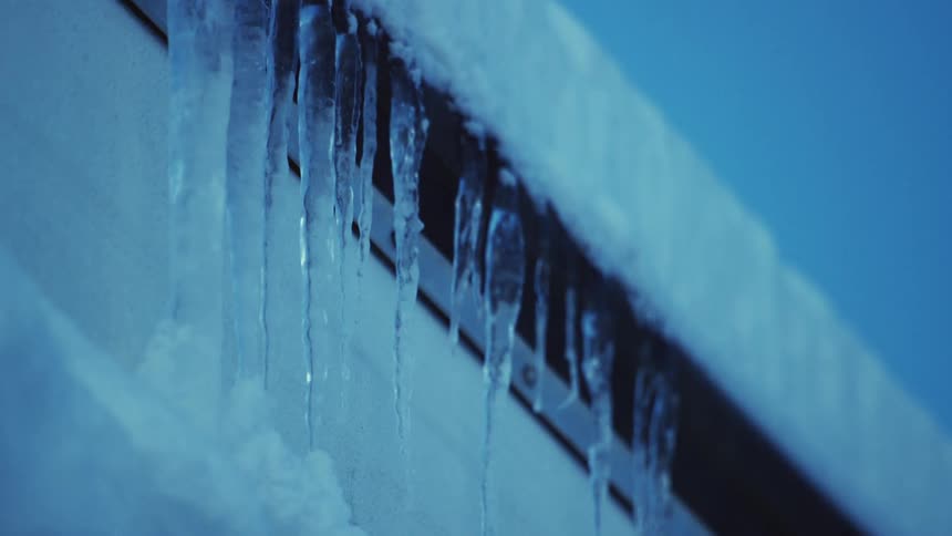 Icicles hang near snow covered roof line