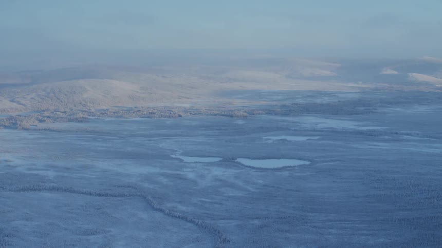 Aerial view of snowy open area and distant mountains
