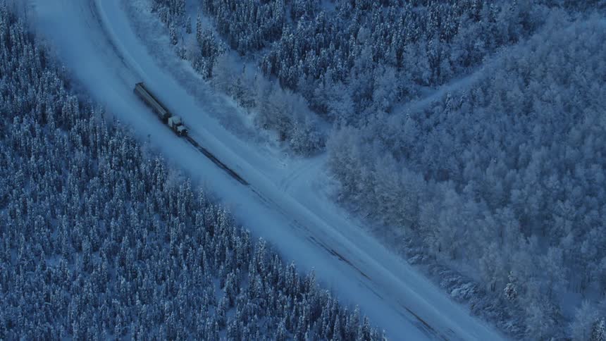 An aerial view of a truck driving in a forest