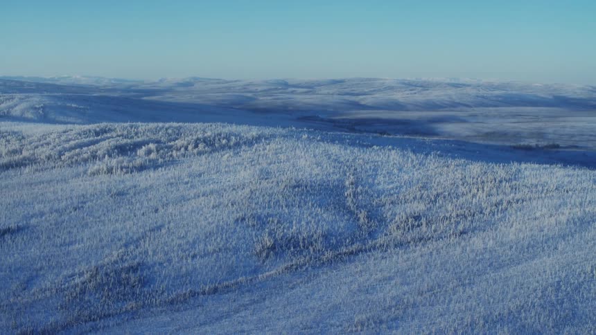 A snow covered hillside and landscape with snowy mountains in the distance
