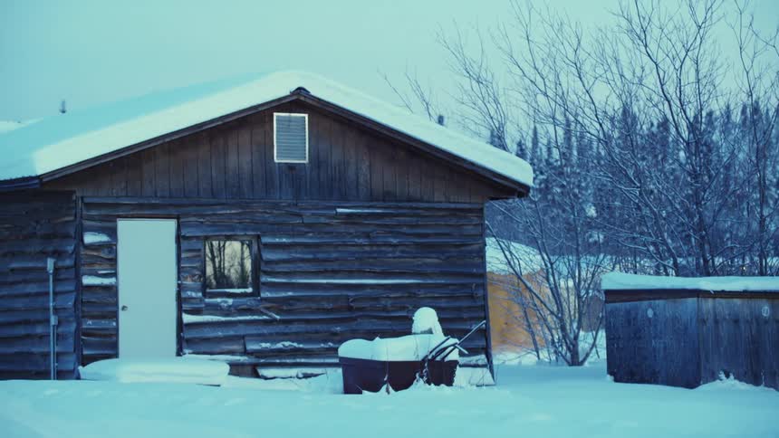A thick blanket of snow covers a log cabin