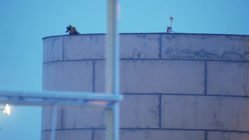 A man welding at the top of a tower