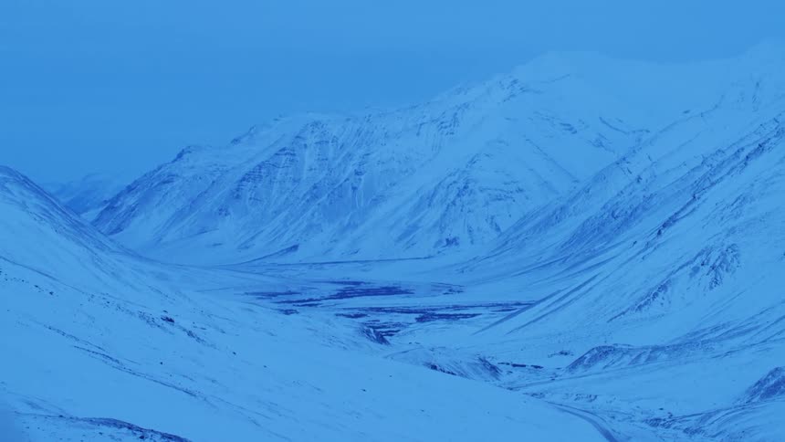The mountains and stream are covered with snow