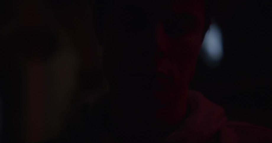 An up close of a mans face lit up by red light with his eyes closed