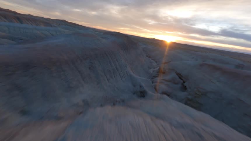 Drone shot aerial view of the camera rushing over valleys and canyons in the desert at evening
