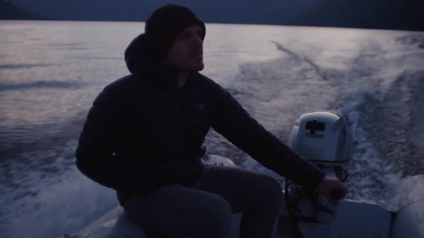 Man drives a outboard motor boat on a lake at evening