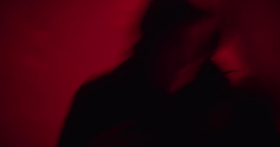 Man shadow boxes while bobbing and weaving under colored lighting