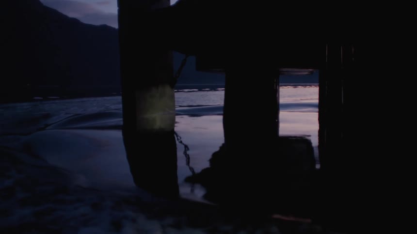 Wake of a boat sailing around a platform on a lake at evening