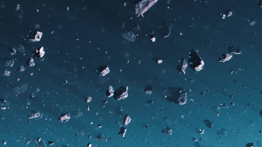 Asteroids are moving across blue space as a light shines upon them