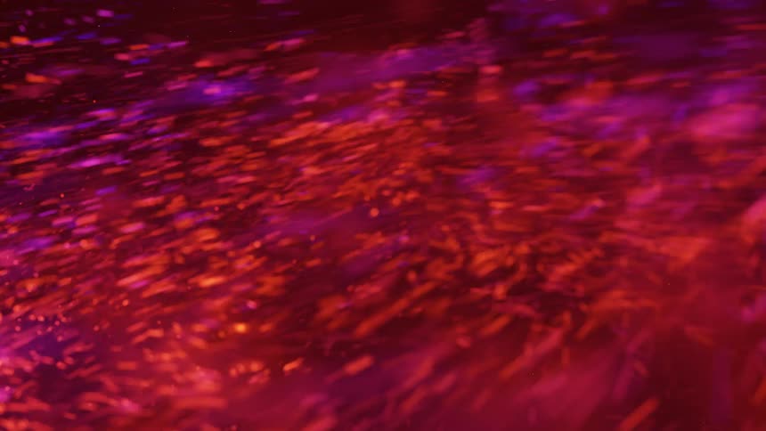 Glowing particles spin in a red swirling vortex in the darkness