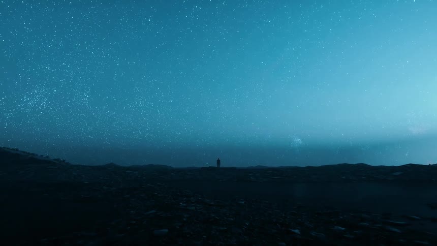 Silhouette of a person standing on high ground under a starry blue sky