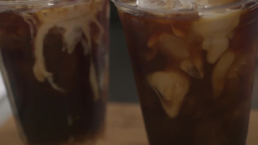 Cream is poured into two iced beverages