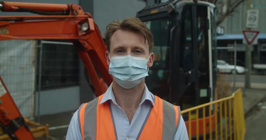 A construction worker standing in front of heavy equipment