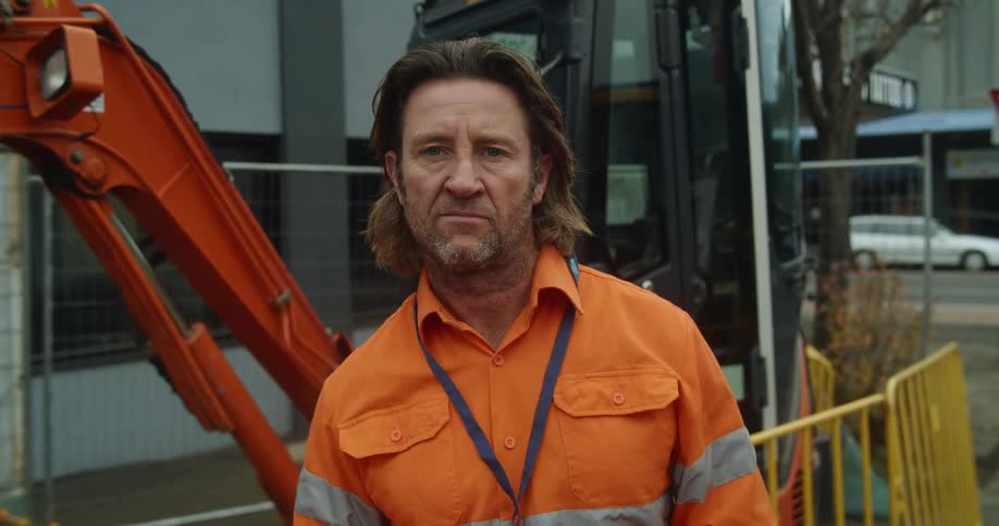 A man standing in a city with buildings and vehicles in the background