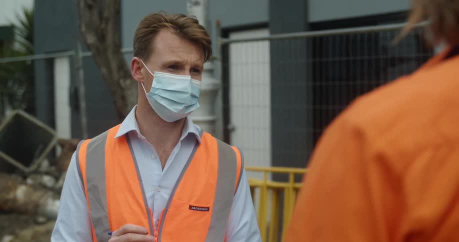 A man with a notebook telling someone else how to do something at a construction site