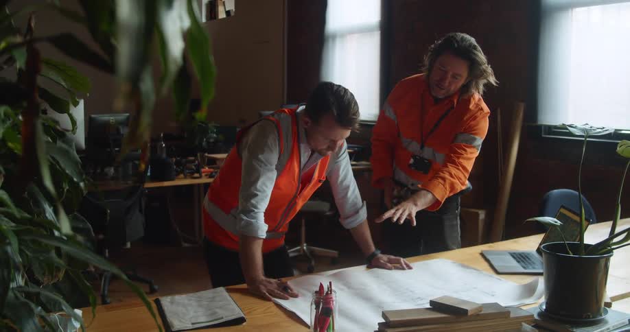 Coworkers having discussion over blueprints on desk in office