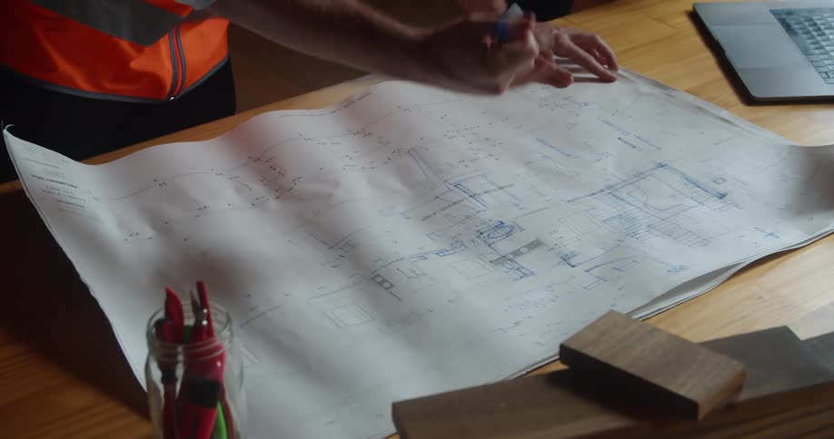 A man in an office looks at blueprints