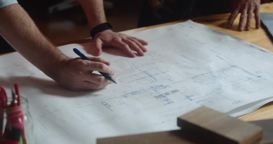 A boss and an employee looks at a blueprint together