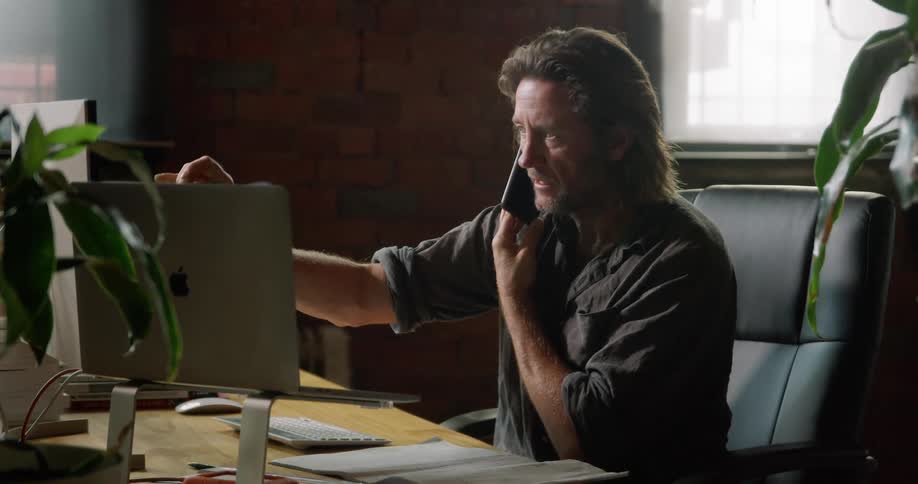 Male architect sitting at the table makes a telephone conversation in the office