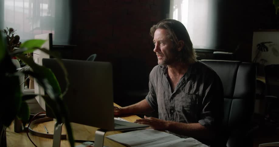 A man sitting at his desk in front of a computer talking