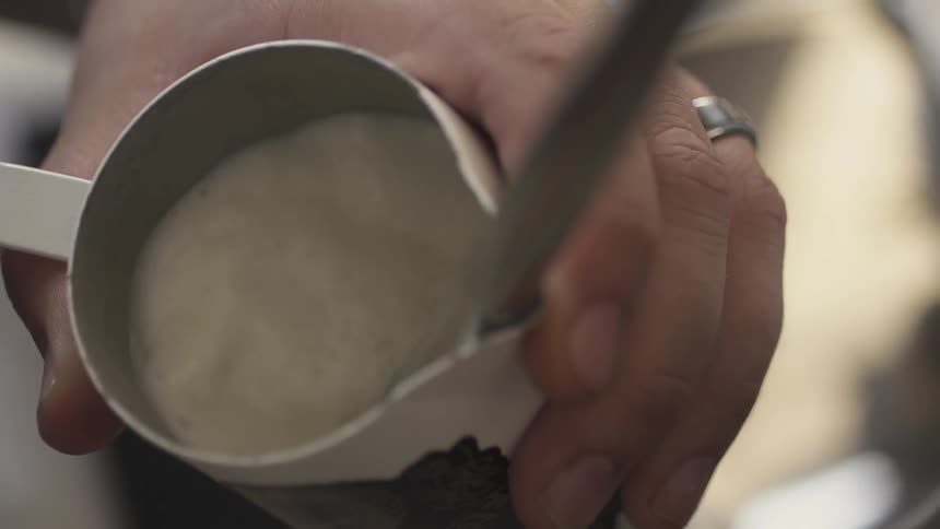 A person fills a cup with milk