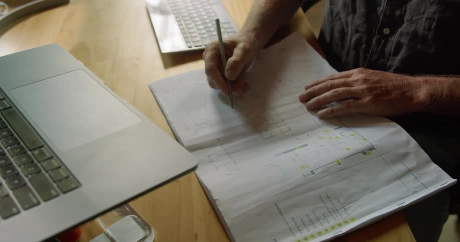 Man types on a laptop then writes in a notebook