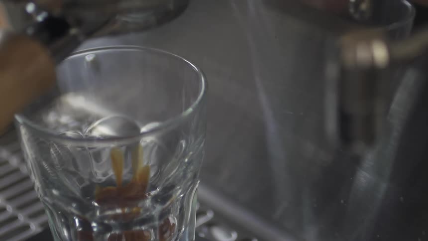 Coffee is pouring from a machine into a glass