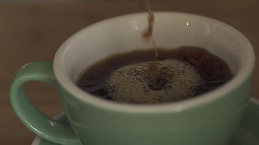 Coffee is poured into a green mug