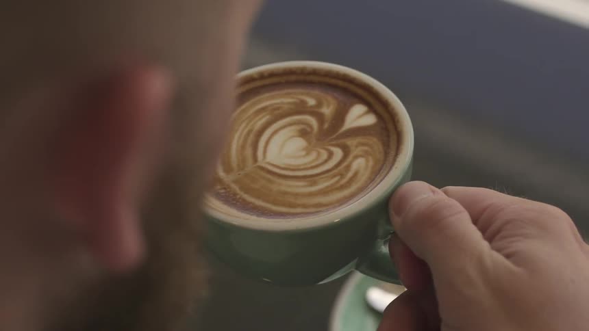 A man lifts a cup of coffee to his lips