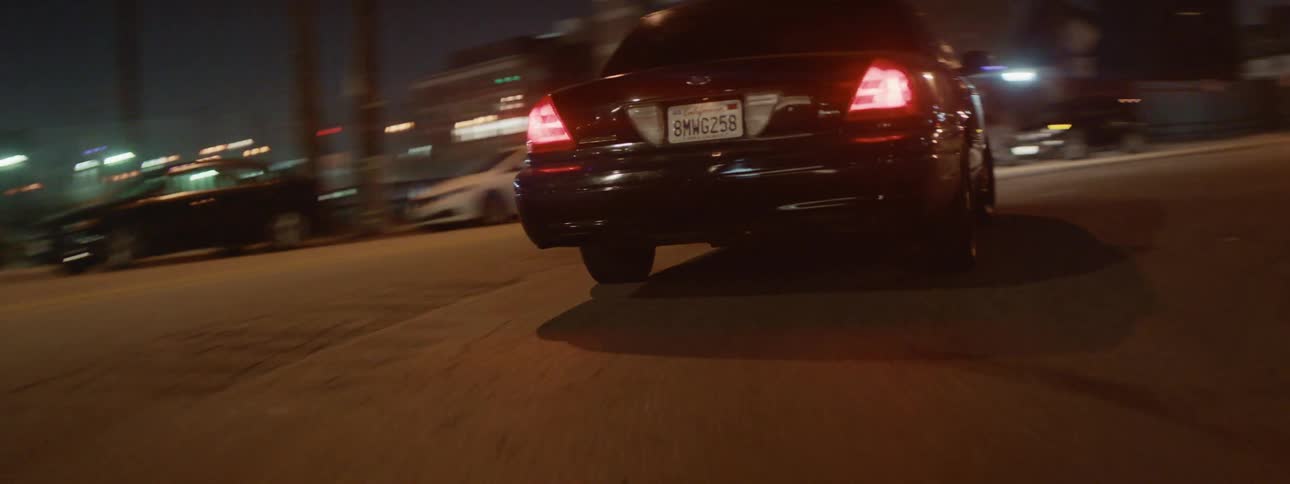 A car travels along the streets of a city at night